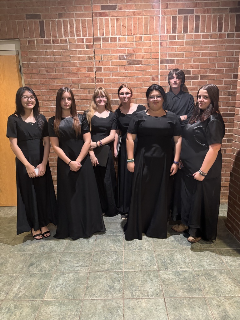 Students dressed in black formal attire pose in a hall.
