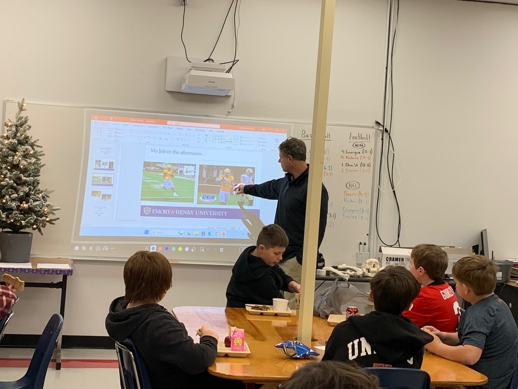A man speaks with a group of students in a classroom.