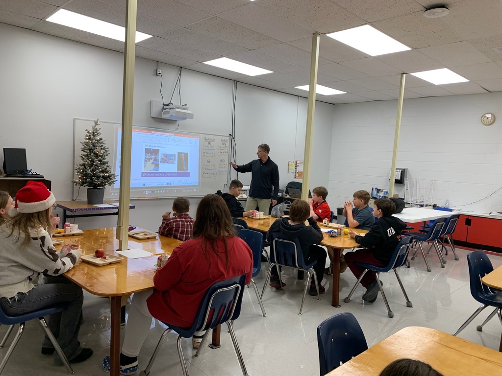 A man speaks with a group of students in a classroom.