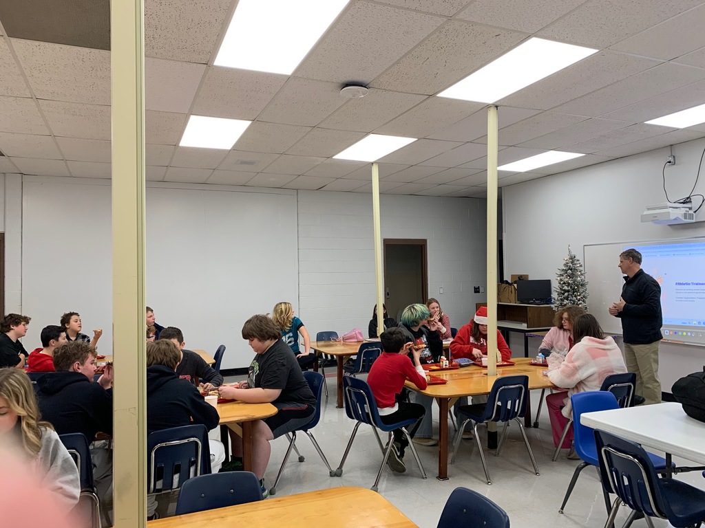 A man speaks with a group of students in a classroom.
