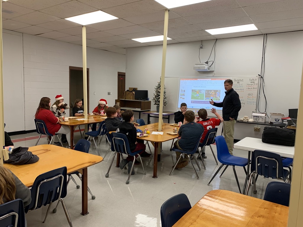 A man speaks with a group of students in a classroom.