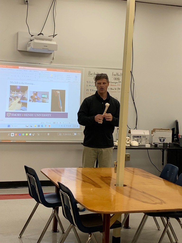 A man speaks with a group of students in a classroom.