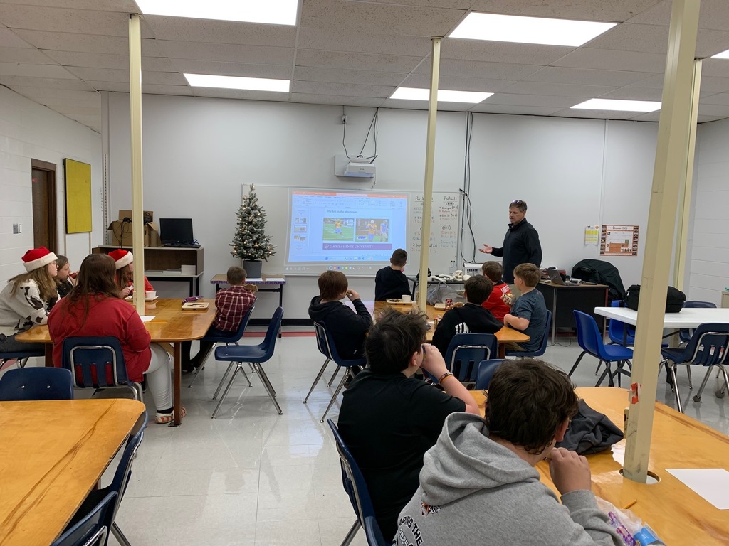 A man speaks with a group of students in a classroom.