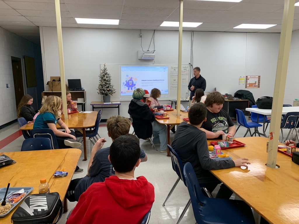 A man speaks with a group of students in a classroom.