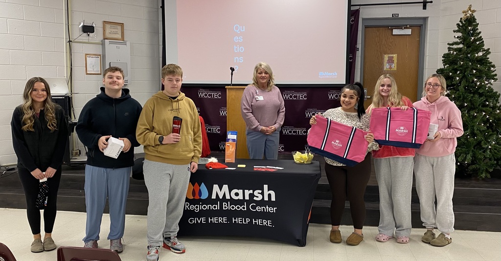Students pose with prizes given to them by a woman representing Marsh Regional Blood Center.