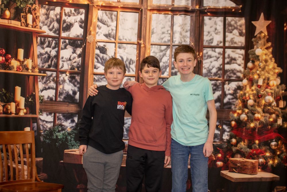 Three students pose in front of a snowy winter backdrop.