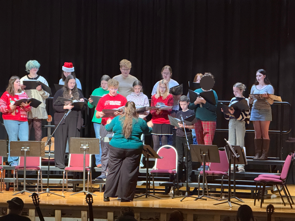 Students sing on a stage.