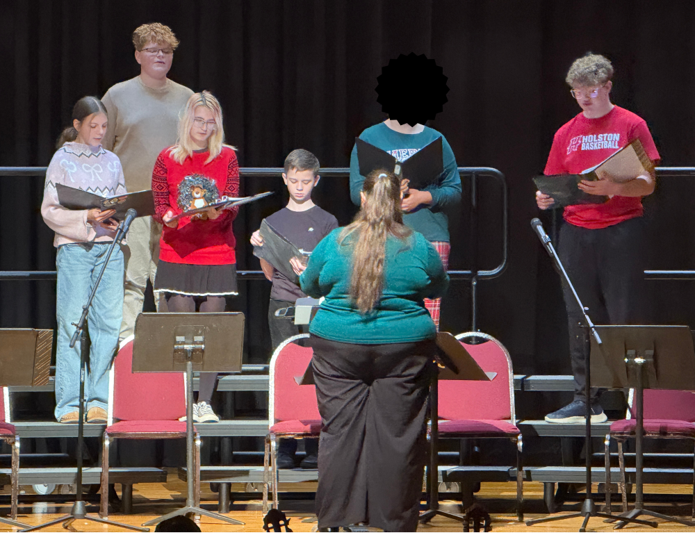 Students sing on a stage.