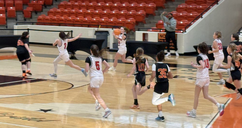 Girls play basketball in a gym.