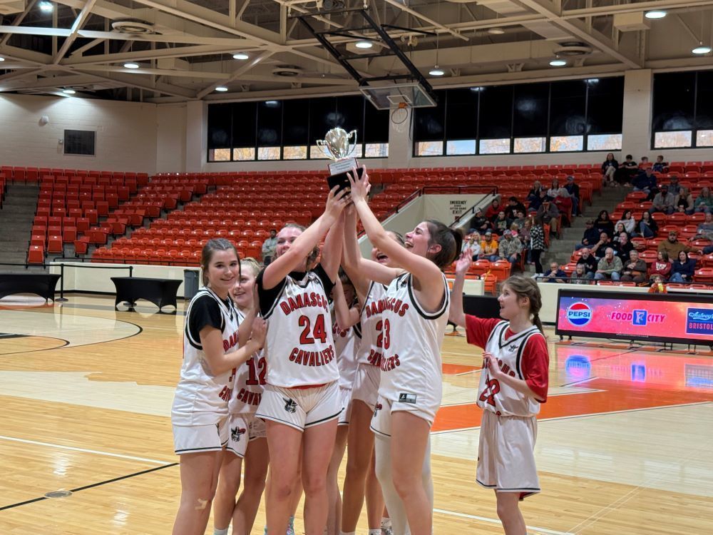A girls basketball team hoists a trophy.