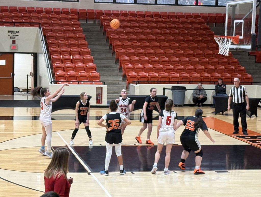 Girls play basketball in a gym.