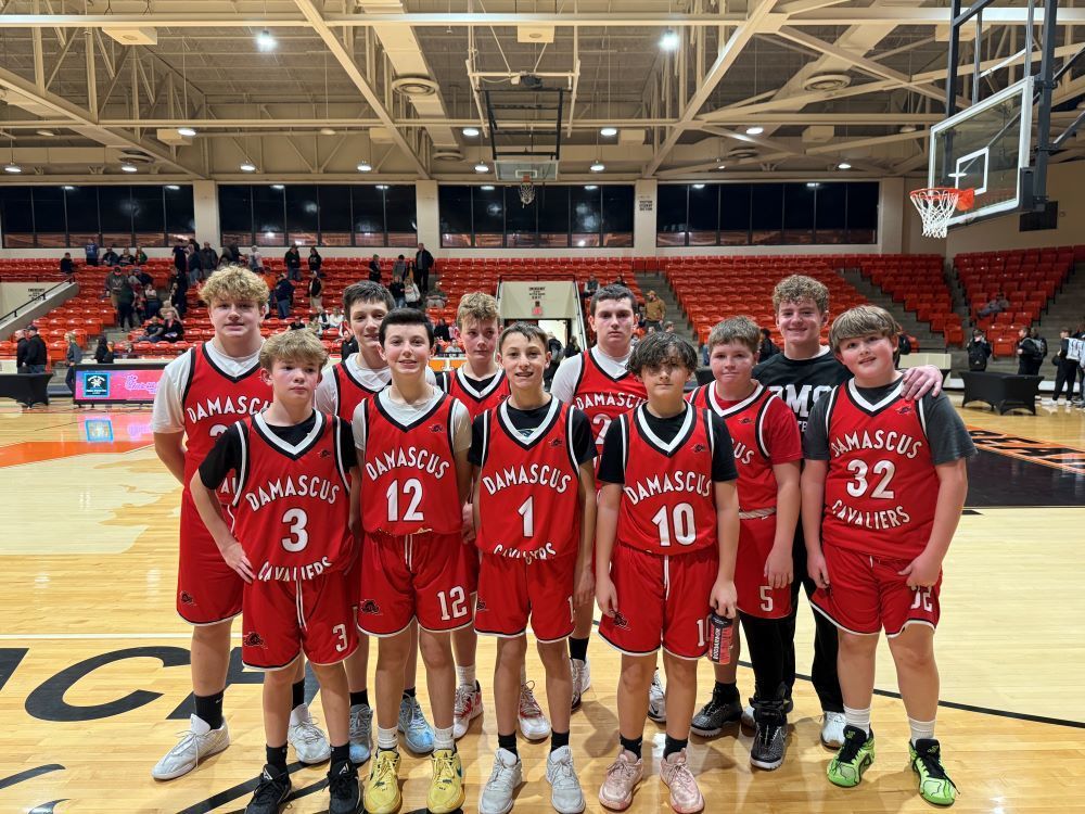 A boys basketball team poses in a gym.