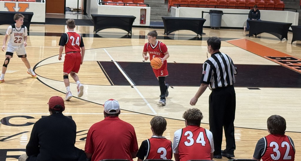Boys play basketball in a gym.