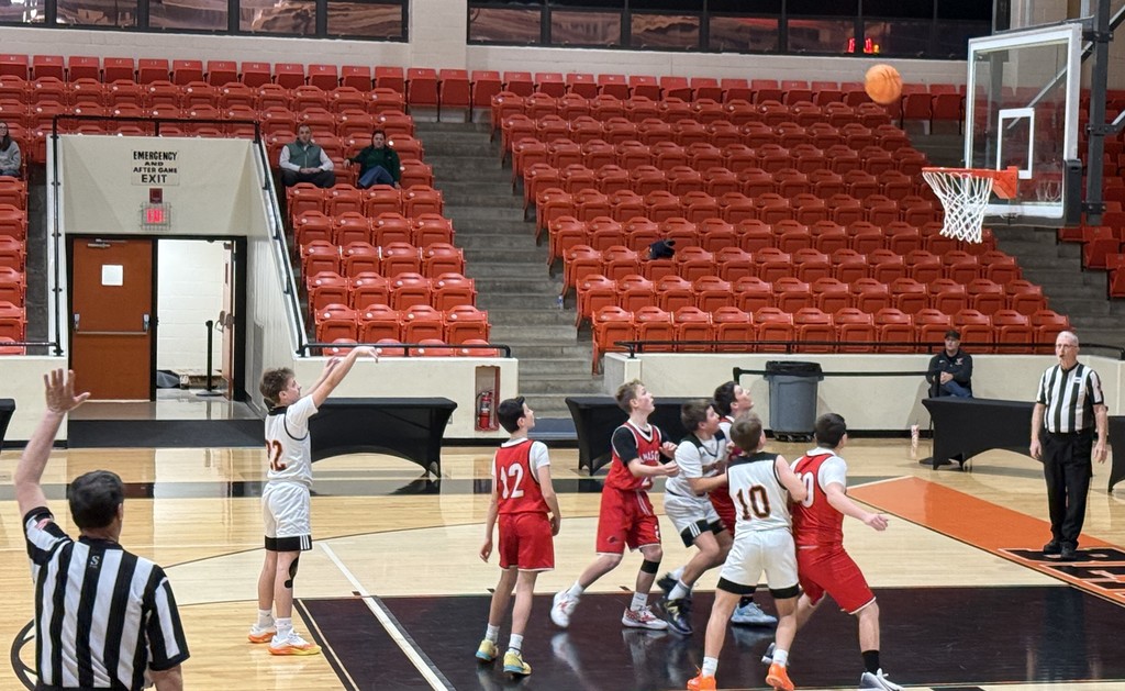 Boys play basketball in a gym.
