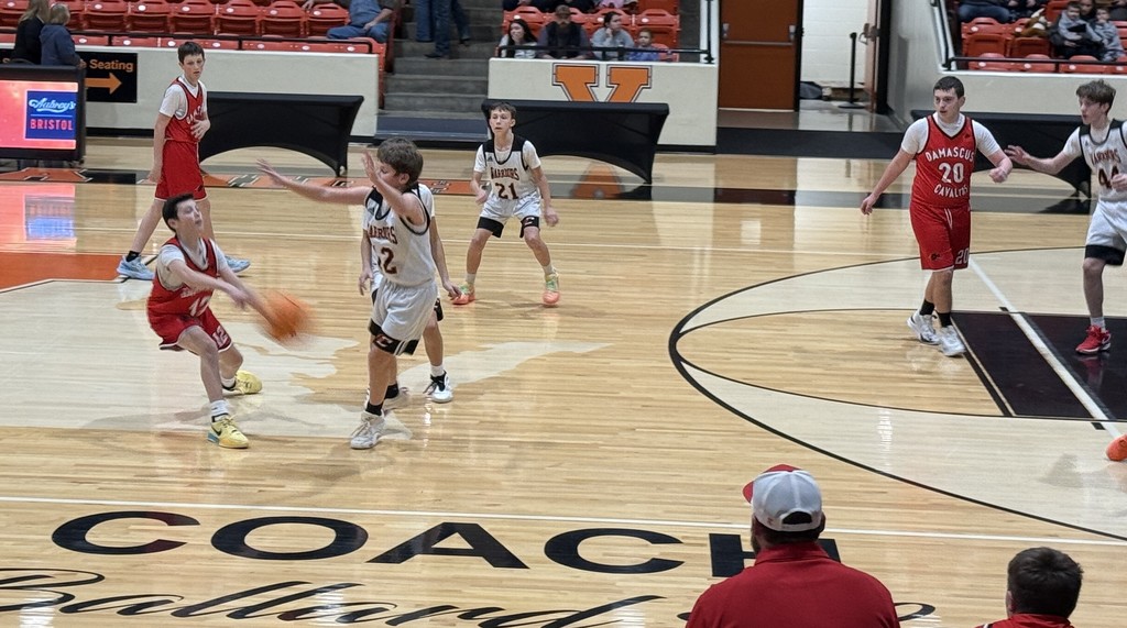 Boys play basketball in a gym.