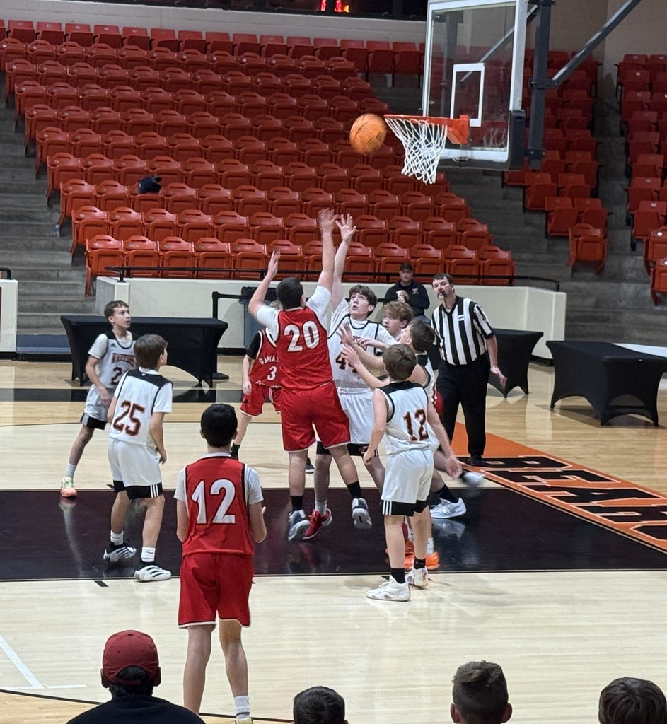 Boys play basketball in a gym.