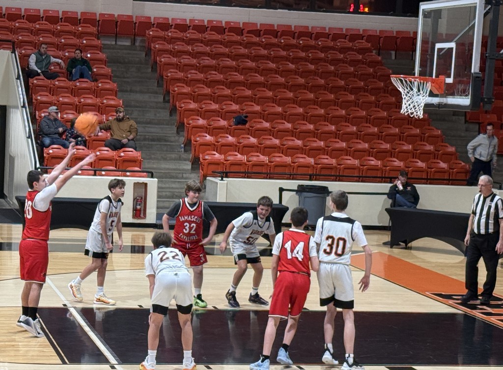 Boys play basketball in a gym.