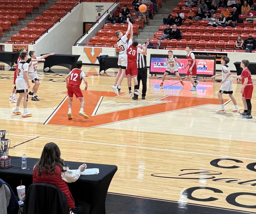 Boys play basketball in a gym.