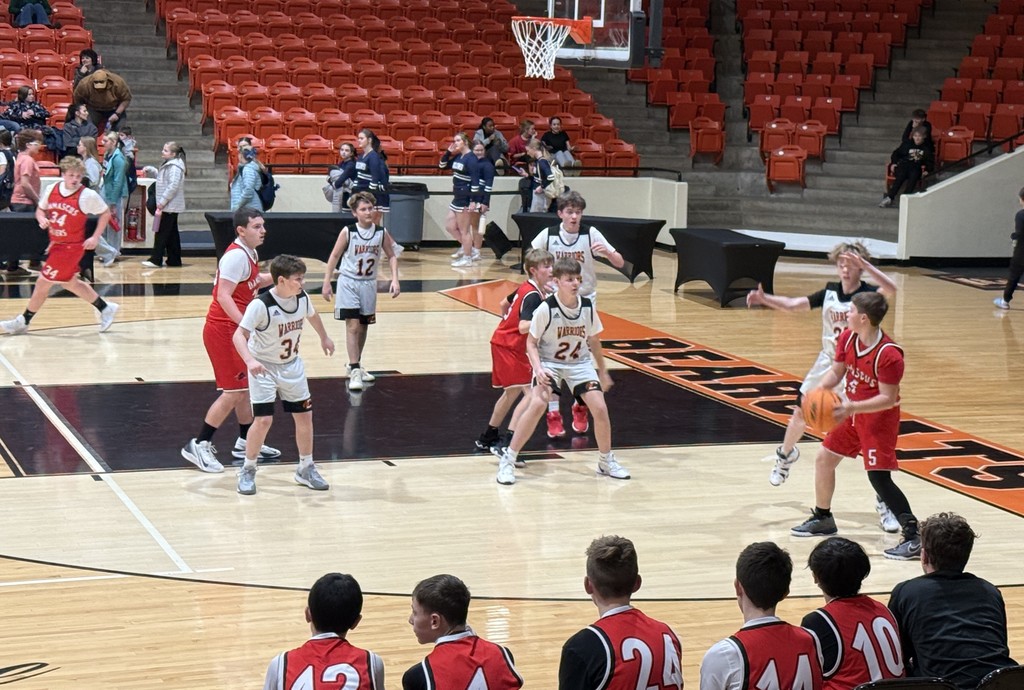 Boys play basketball in a gym.