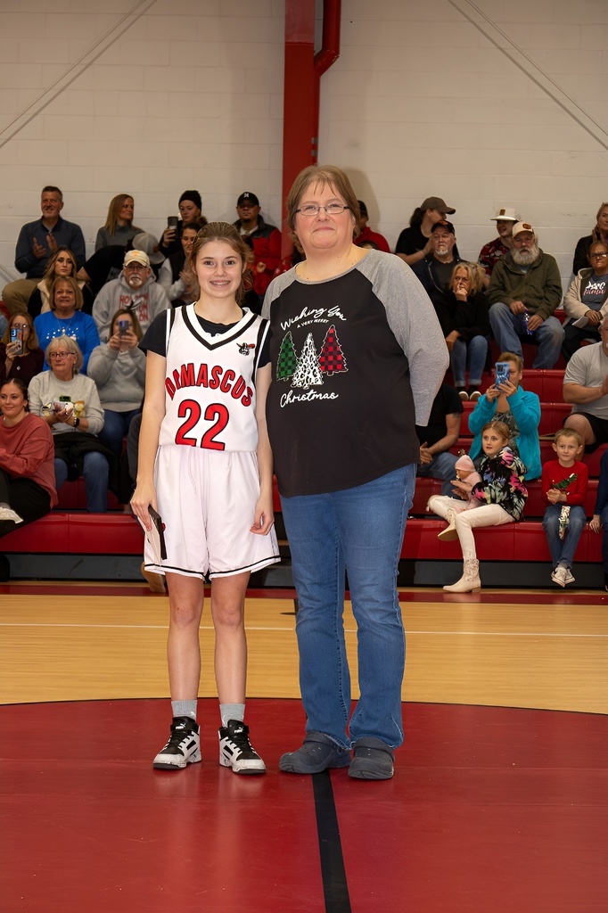 A teacher stands with a student athlete in a gym.