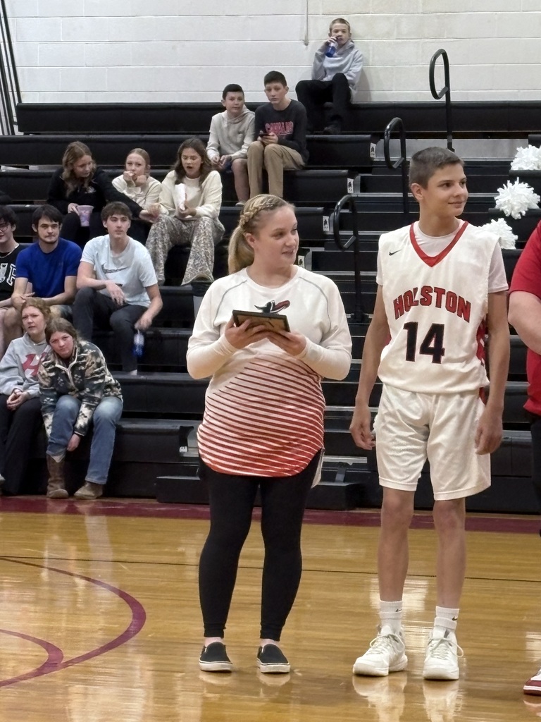 A teacher stands with a basketball player in a gym. 