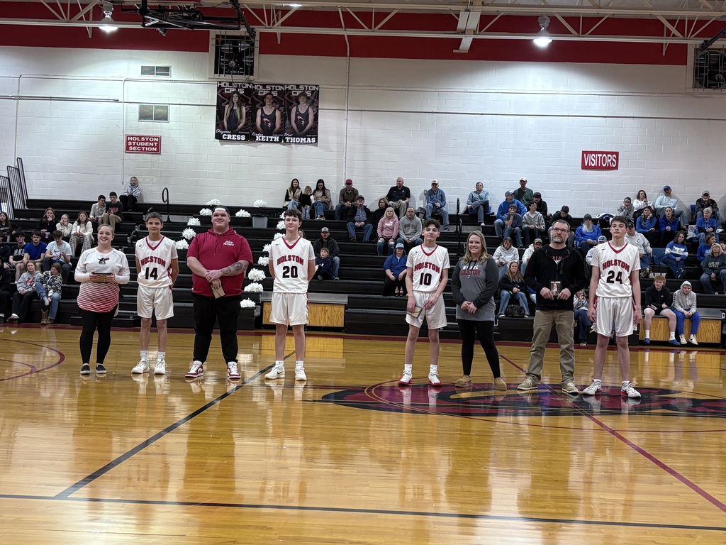 A teacher stands with a basketball player in a gym. 