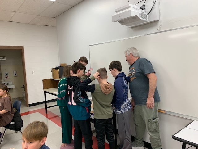 Students look at fishing bait in a classroom.