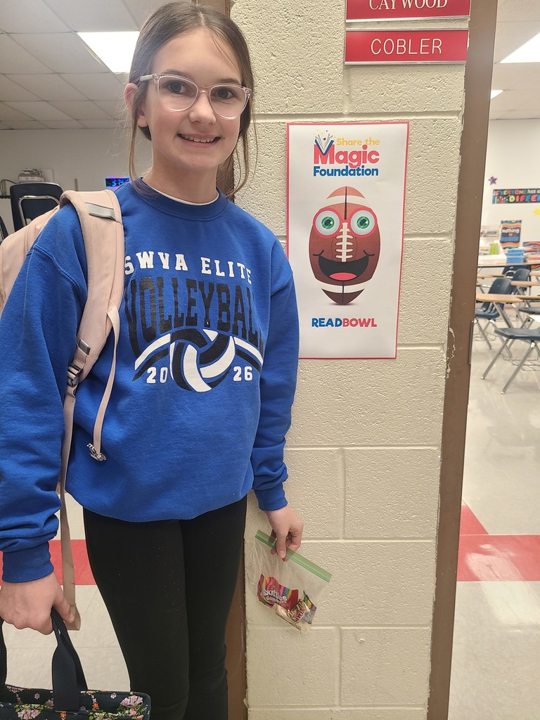 A student poses in a school hallway beside a ReadBowl sign.