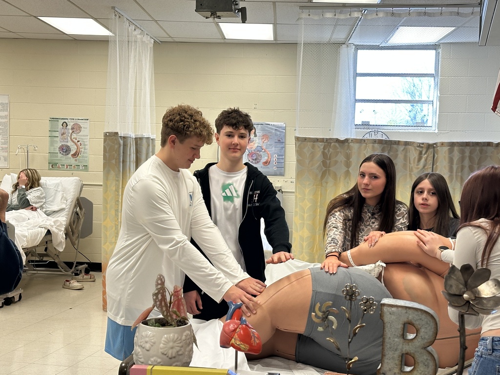 Students work with a manikin in a nursing shop.