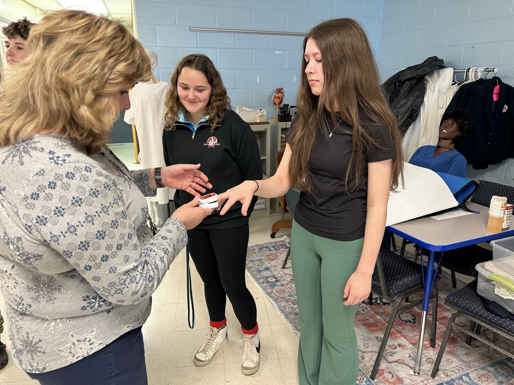 A teacher takes a student's pulse.
