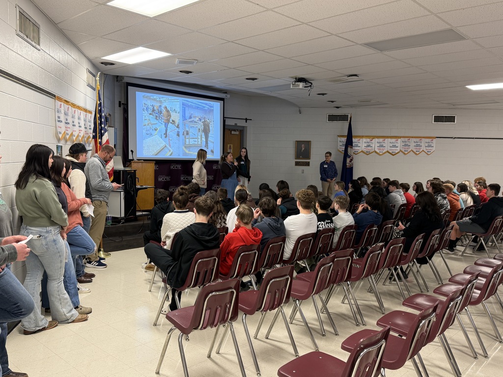 Students speak to a group of younger students in an auditorium.