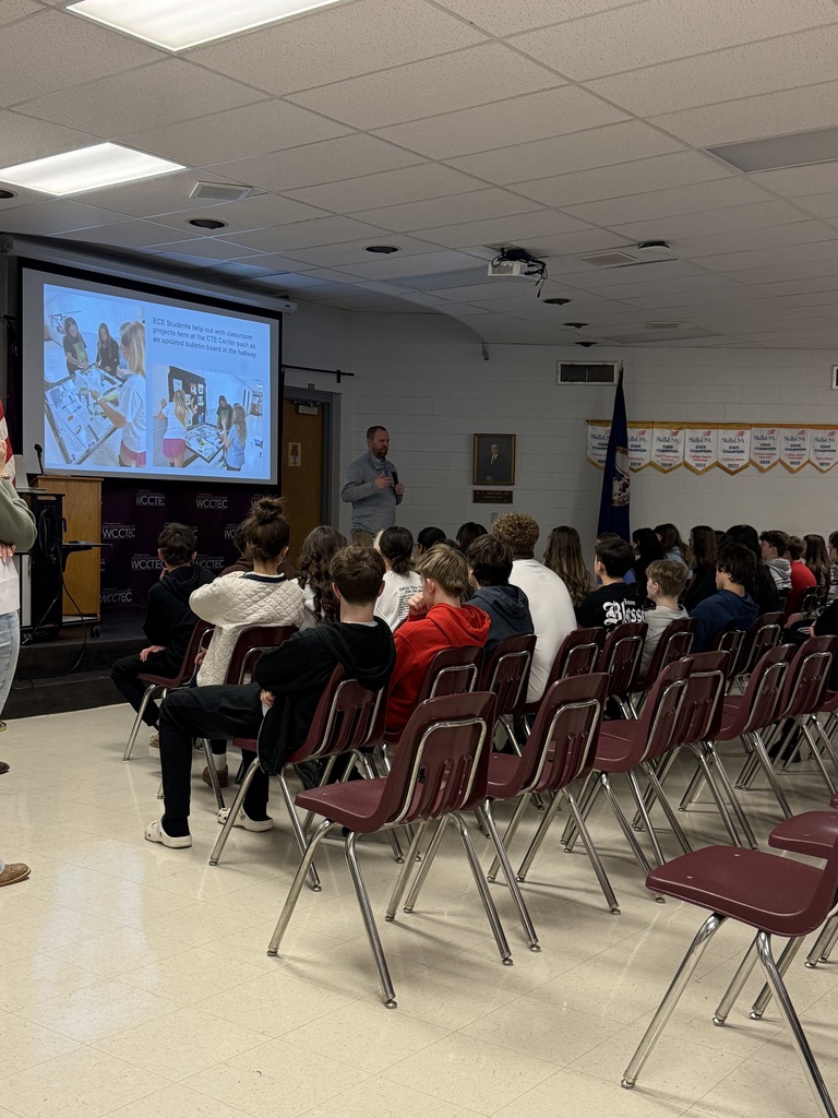 A man talks with a group of students in an auditorium.