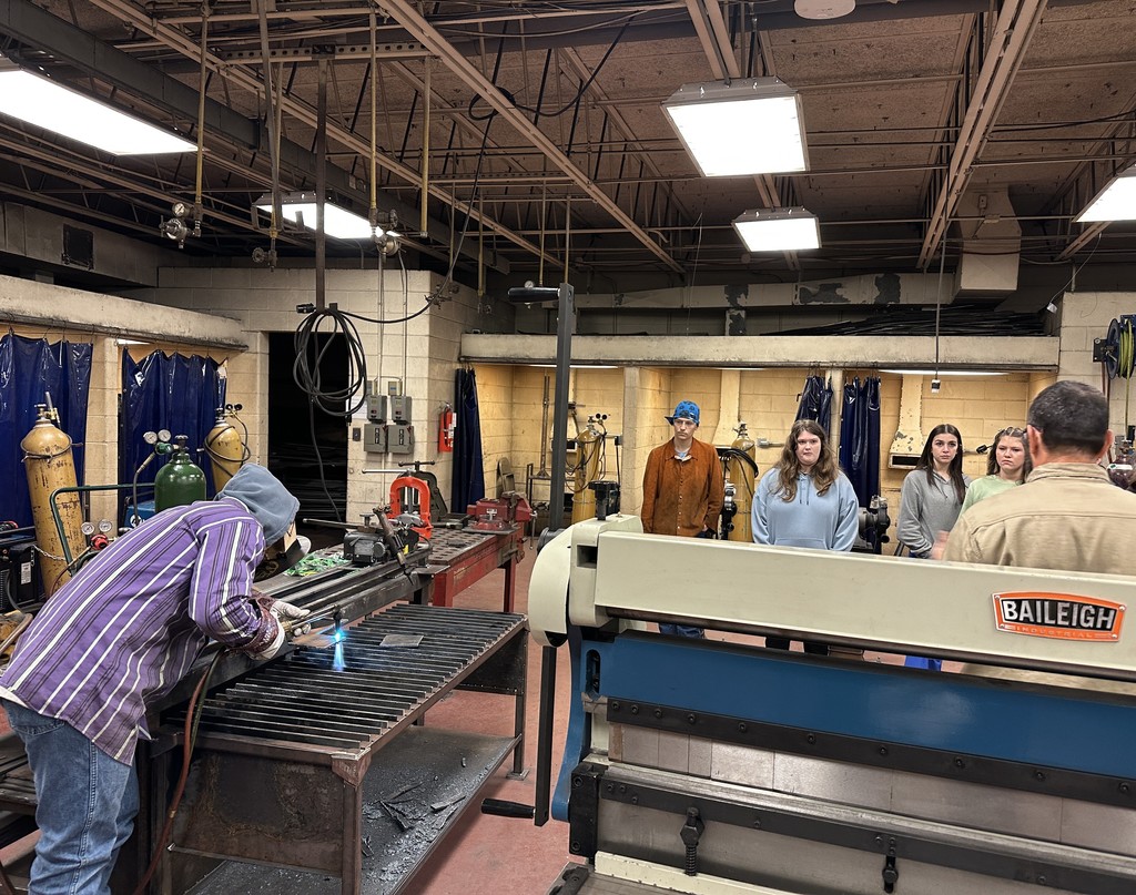 Students observe a welder working on a weld.