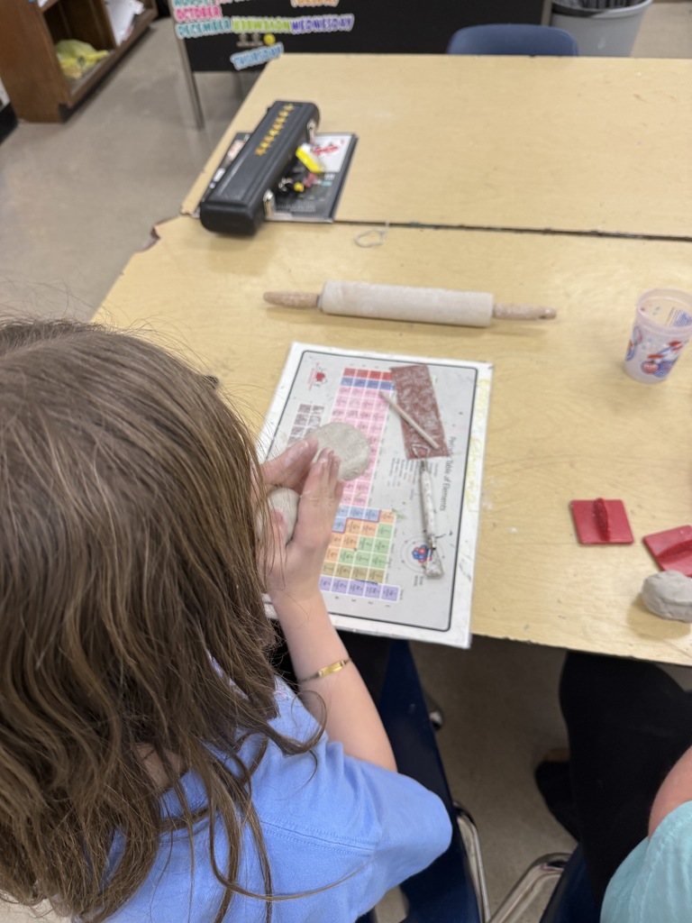 Students work with clay in an art classroom.