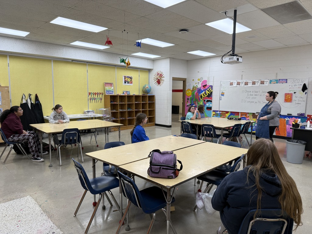 A teacher talks with students in an art classroom.