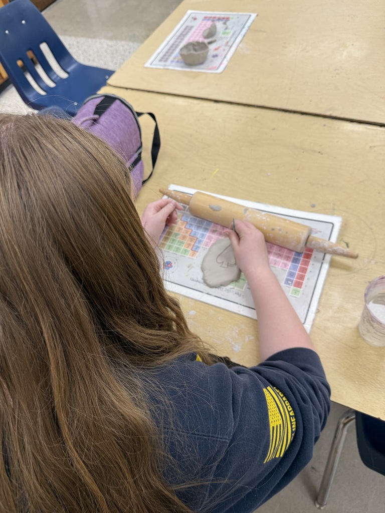 Students work with clay in an art classroom.