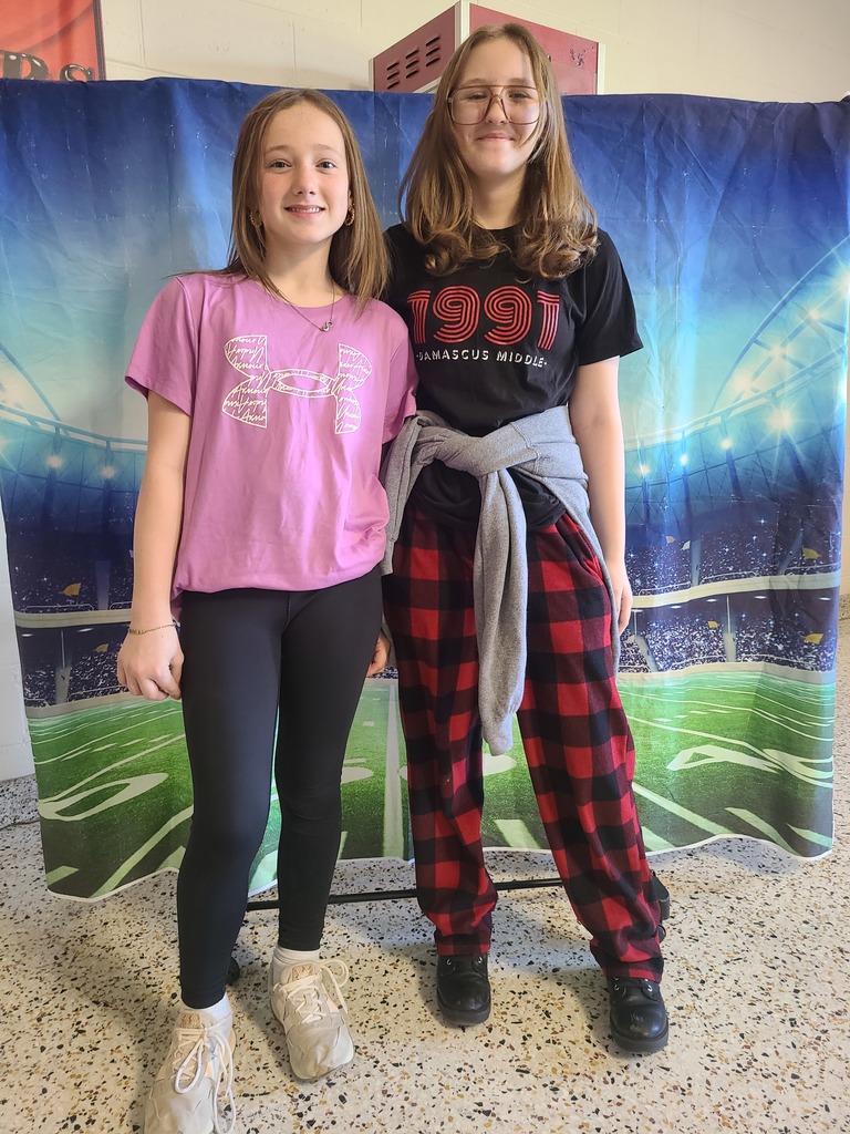 Two students pose in front of a football background.