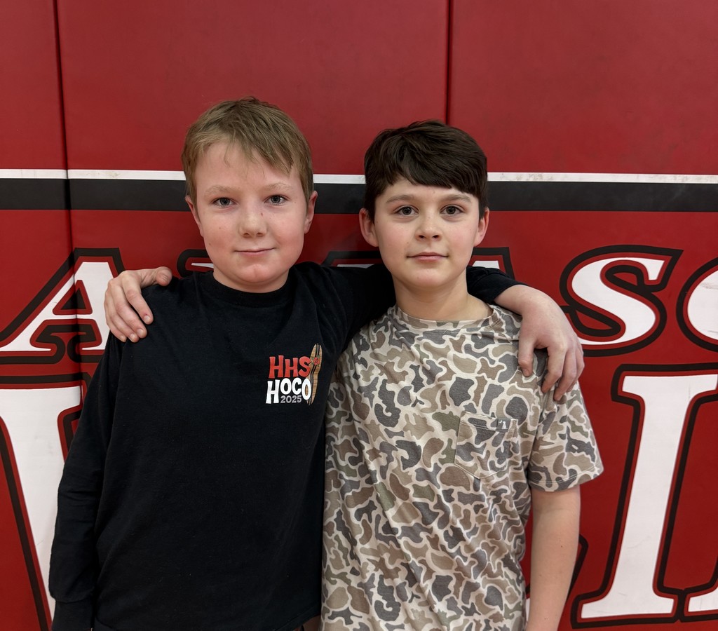 Two boys stand in a gym.