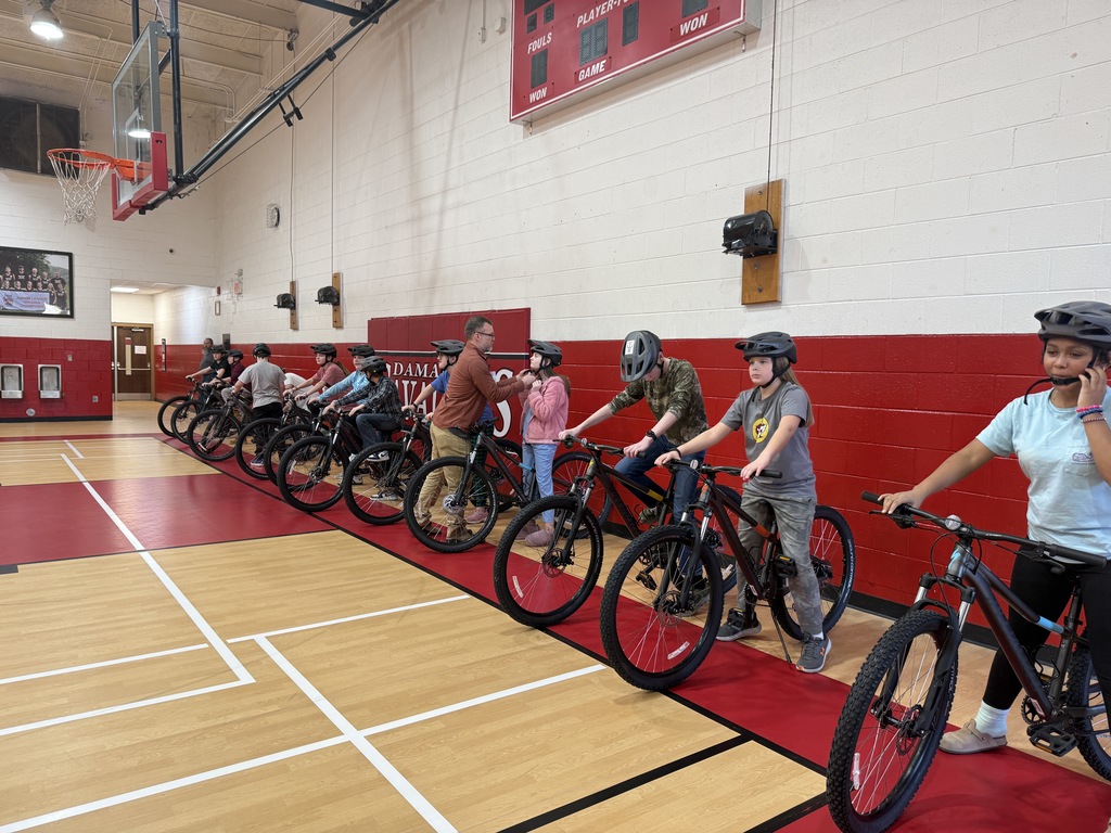 Students practice bike skills in a gym.