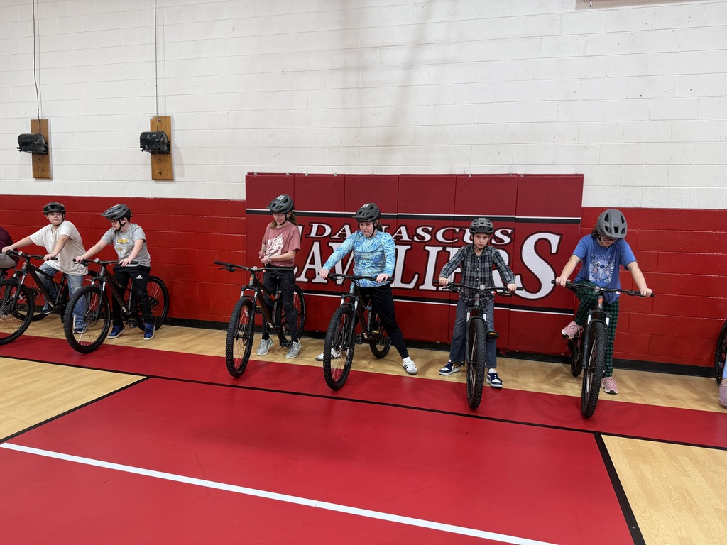 Students practice bike skills in a gym.