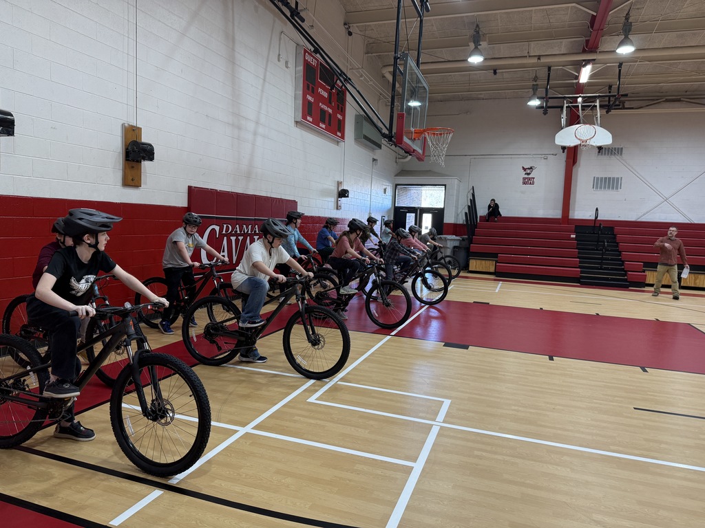 Students practice bike skills in a gym.