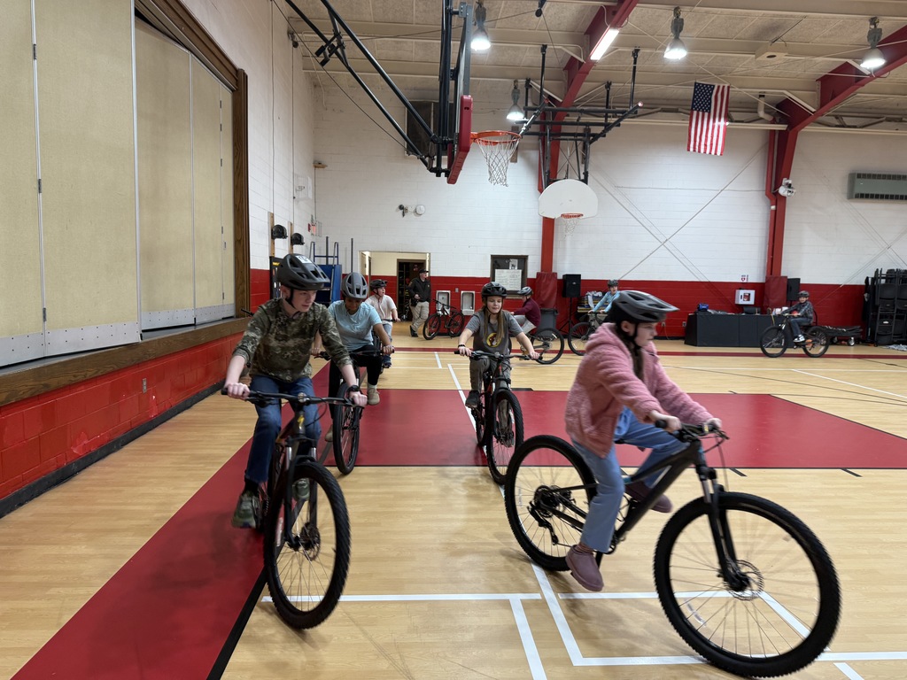 Students practice bike skills in a gym.