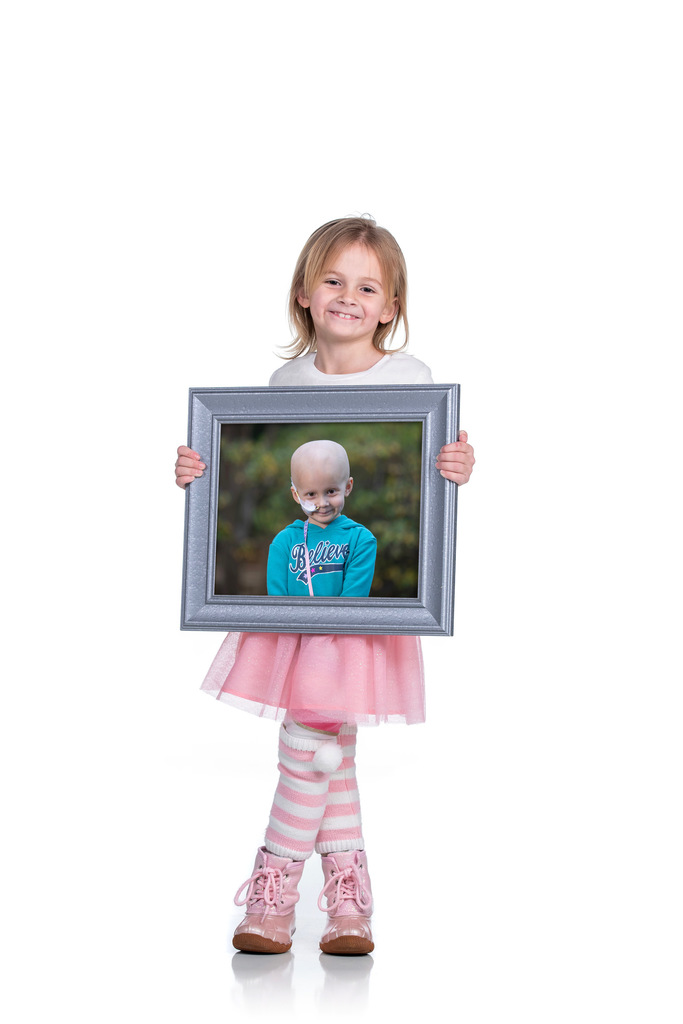 A girl holds a picture of her younger self when she was sick.