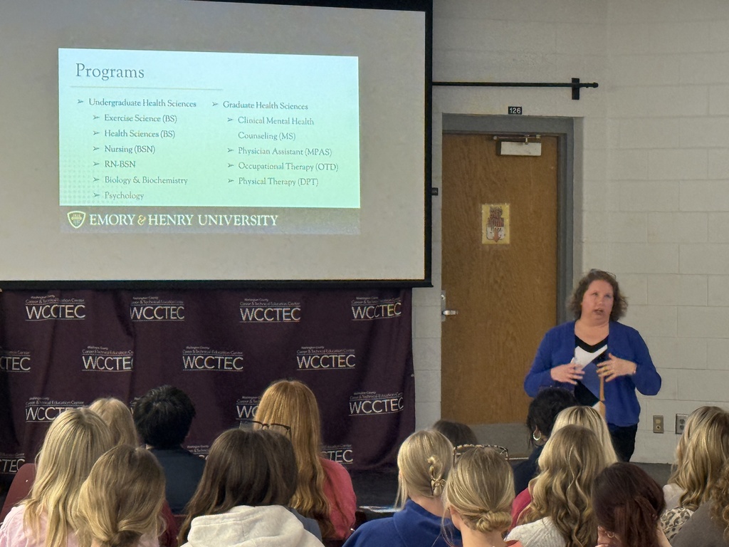 A woman talks with students in an auditorium.