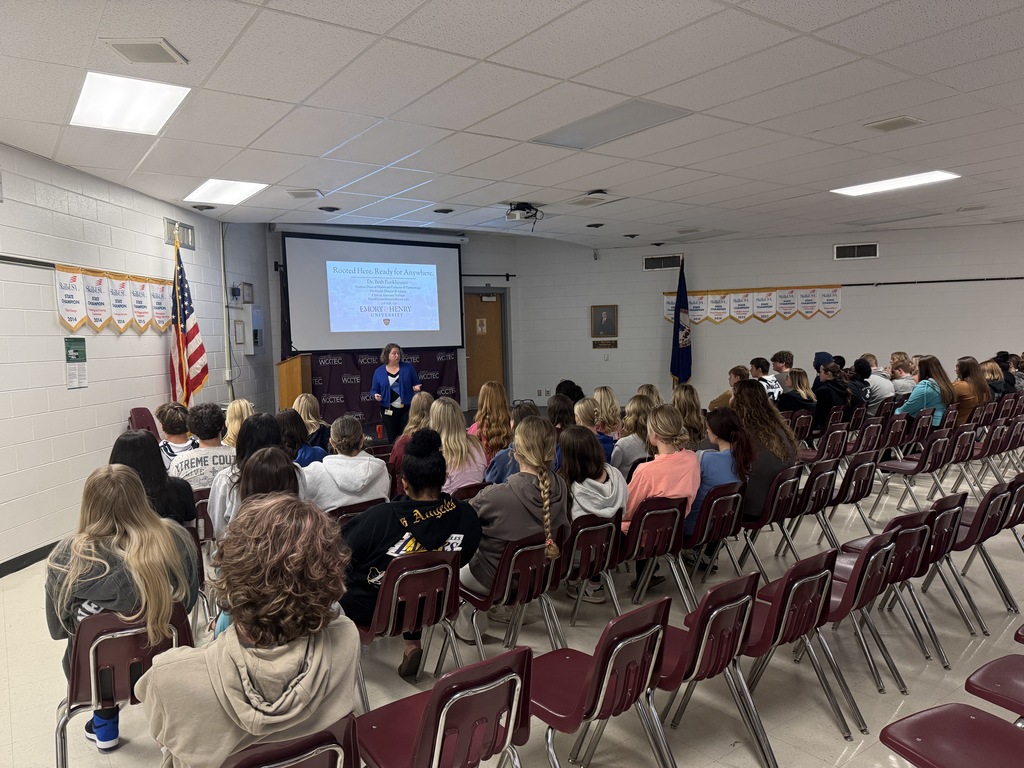 A woman talks with students in an auditorium.
