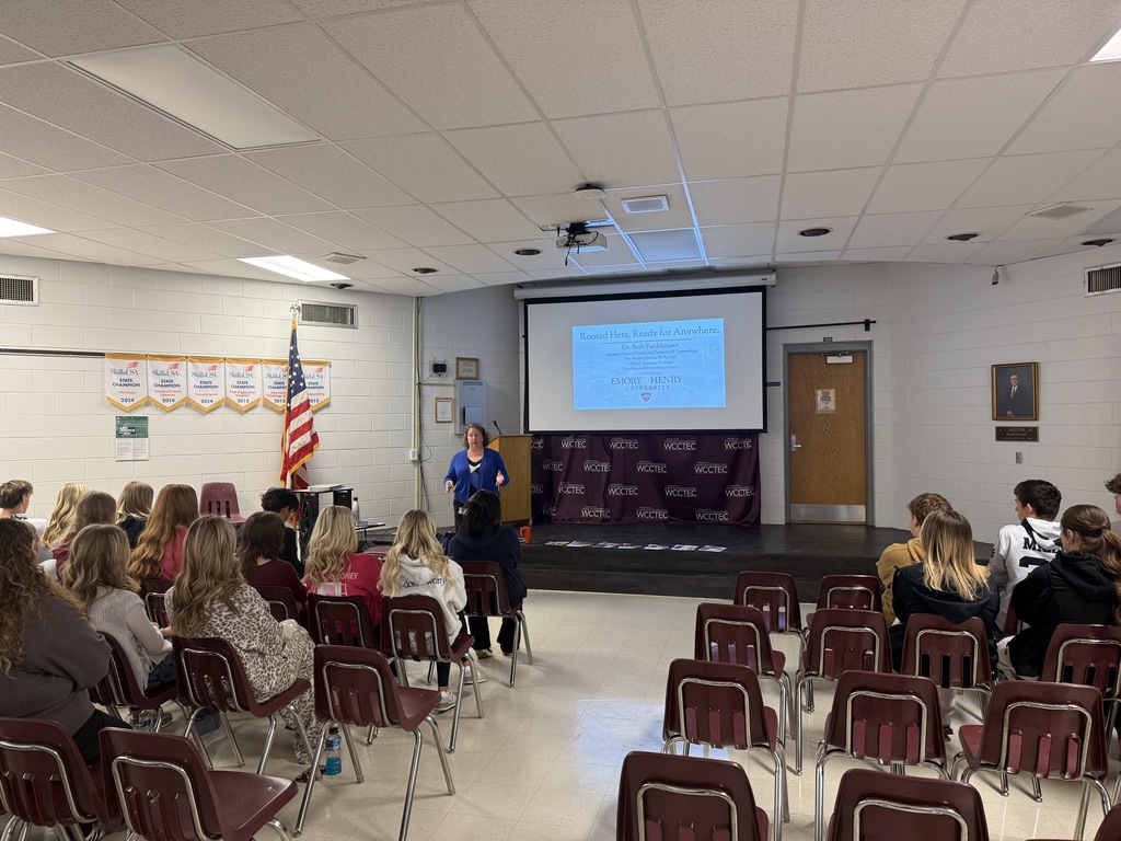 A woman talks with students in an auditorium.