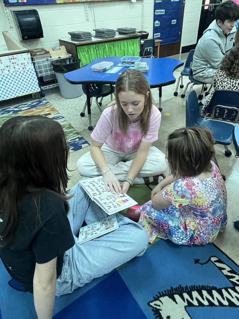 An older student reads to a younger student.