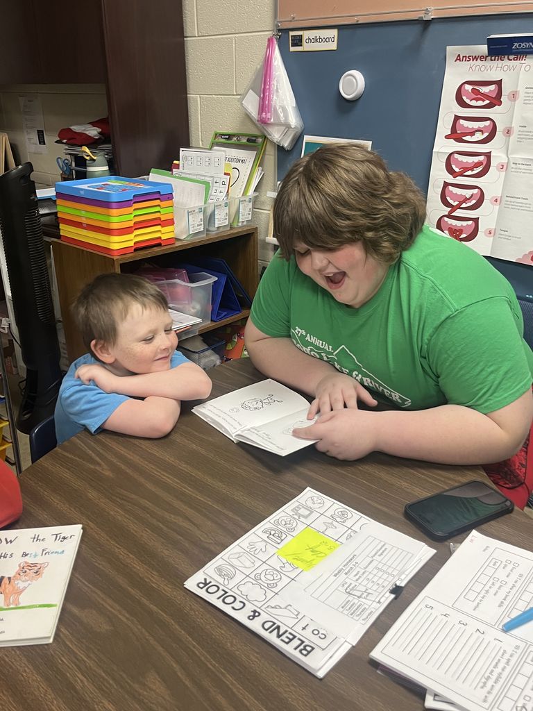An older student reads to a younger student.
