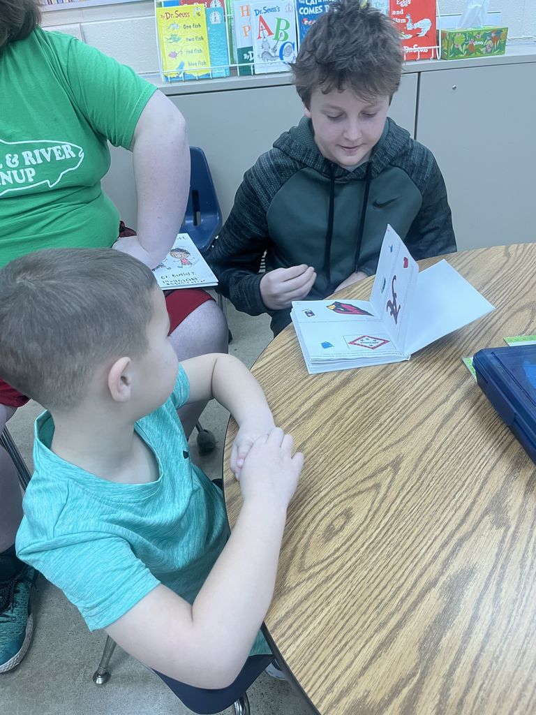 An older student reads to a younger student.