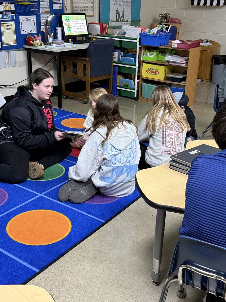 An older student reads to a younger student.